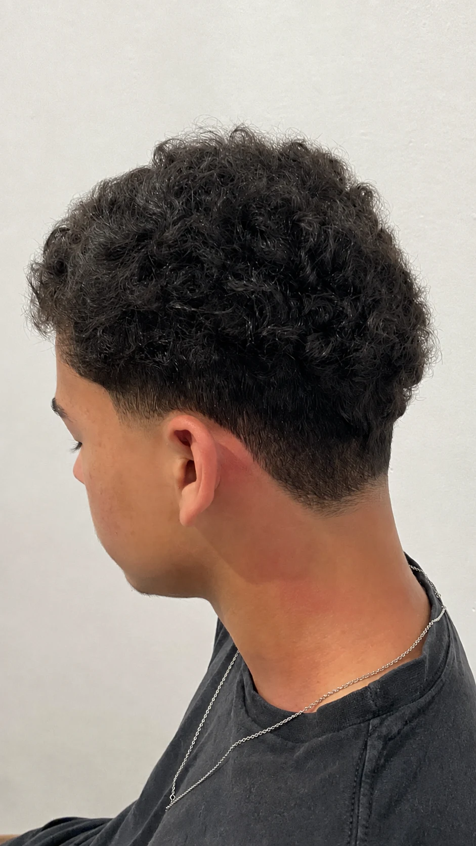 Corte cacheado da Ferreira’s Cuts em vista lateral, com retoque leve de frizz solicitado pelo proprietário